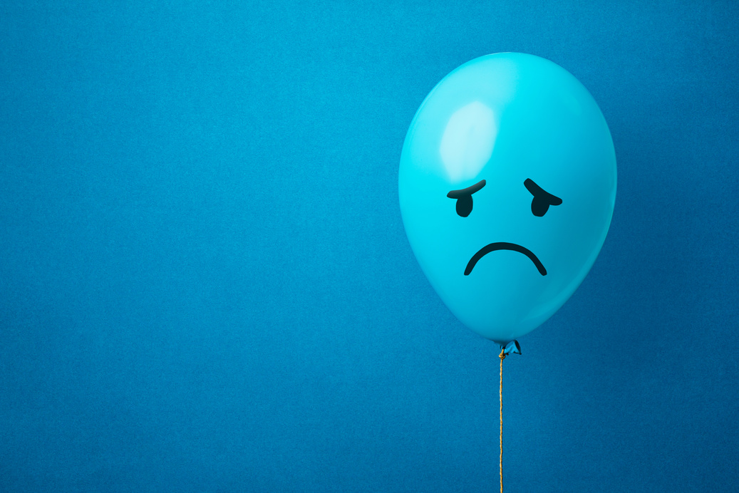 Sad Face Drawn on Blue Balloon on Blue Background